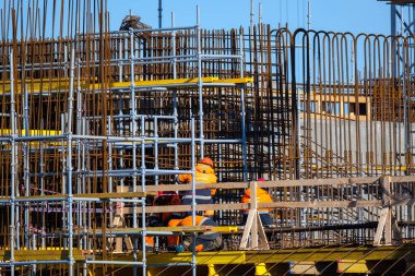 Köprüde, metal direklerin yanında tanınmayan işçiler.