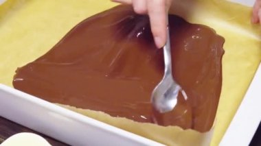 Kırpılmış kadın çikolatayı kağıda sürüyor.