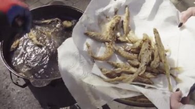 Ürün satıcıları tepsiye kızarmış balık koyuyor.