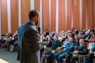 Erkek sunucu seminerde seyircilere sesleniyor