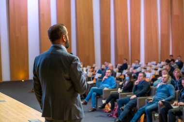 Erkek sunucu seminerde seyircilere sesleniyor