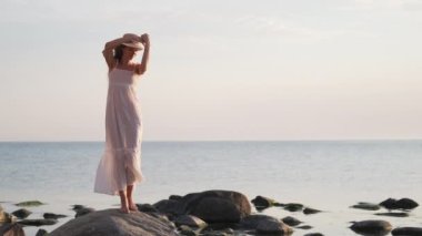 Romantic female in white dress dancing on coast