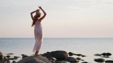 Romantic female in white dress dancing on coast