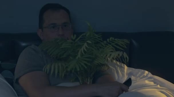 Людина з рослиною дивиться страшний фільм — стокове відео
