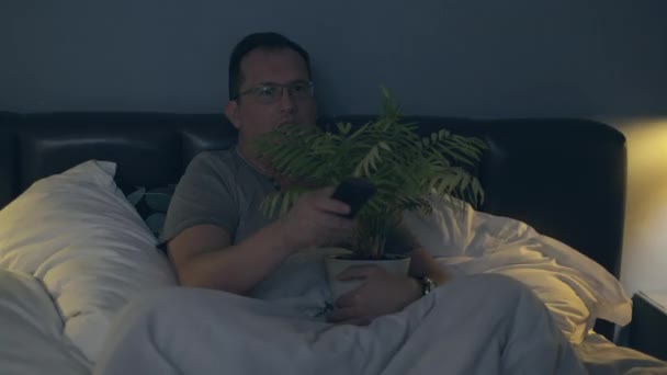 Man with plant watching scary movie — Stock Video