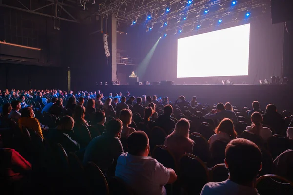 Audience sitting in front of stage with screen — Stock Photo, Image