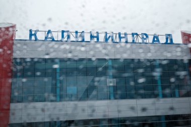 Islak uçak penceresinin arkasındaki modern havaalanı