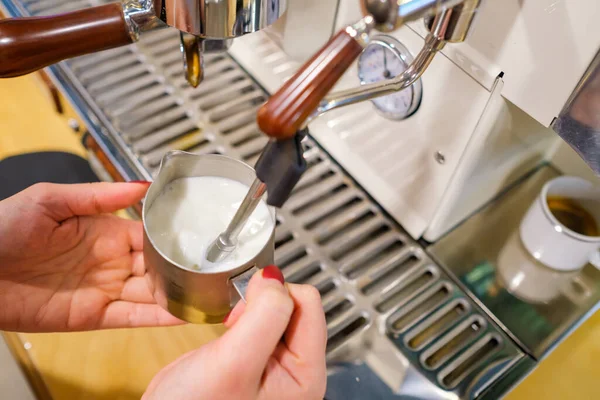 鞭打牛奶在咖啡机的咖啡师 图库图片
