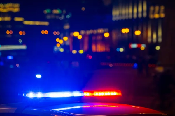 Voiture de police avec des lumières clignotantes avec des couleurs rouges et bleues sur fond flou de la rue de la ville — Photo