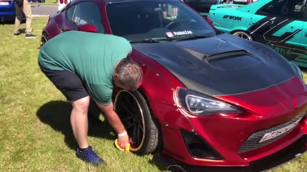 Man wiping wheel of custom car during festival — Stock Video