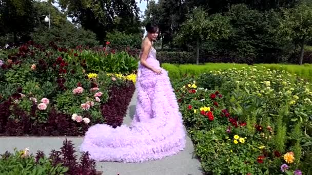 Giovane donna in abito rosa con un lungo treno in posa nel parco — Video Stock