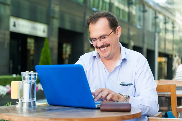 Empresário de meia idade trabalha em laptop — Fotografia de Stock