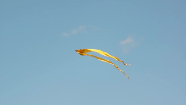 Один желтый змей, летящий в голубом небе — стоковое видео