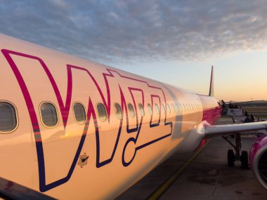 Budapeşte, Macaristan - 12 Eylül 2025: Wizz hava uçağı şafak vakti, canlı havayolu markasıyla birlikte. Yansıtıcı gövde güneş ışığını yakalar.