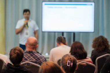 Konuşmacı, bulanık ekran ve katılımcılarla konferans odasında izleyicilere sunar