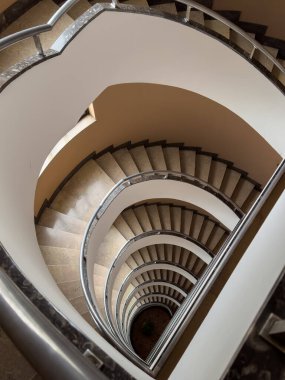 Metal parmaklıklar ve taş basamaklar ile sarmal merdivenleri bükerek dramatik mimari örüntü oluşturma manzarası.