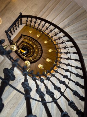 Spiral merdiven iç kısmı siyah demir balyaları eğri boyunca sıcak ampuller çarpıcı bir perspektif ve mimari zarafet yaratır ve izleyiciyi büyük boşluğa davet eder