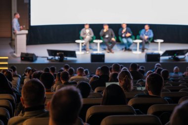Modern konferans salonu, iş semineri, öğrenme, ağ kurma ve mesleki değişim konuşmacılarını dinleyen seyircilerle konferans aşamasında panel tartışması