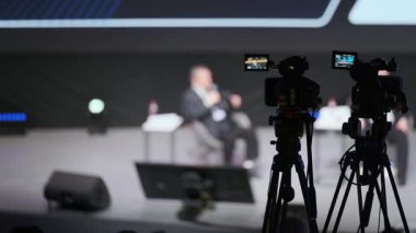 Panelde bulanık hoparlörlerin olduğu sahne olayı ve ön planda çekim kameraları