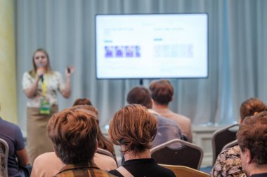 Seyirci konferans sırasında sunucuyu dinler. Hoparlör ekranın yanında slaytlı mikrofon kullanır.