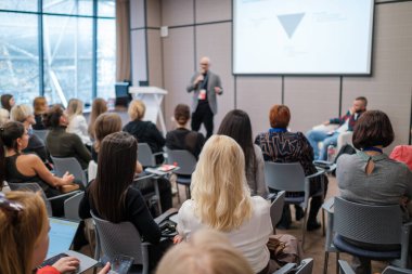 Mesleki konferans, ağ kurma, öğrenme ve modern toplantı alanındaki tartışmalar sırasında sunucuyu dinleyen iş dünyası dinleyicileri.