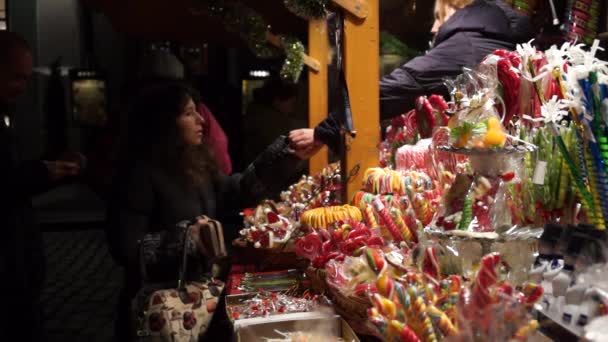 Los turistas compran dulces en un quiosco de dulces en el mercado de Navidad — Vídeo de stock