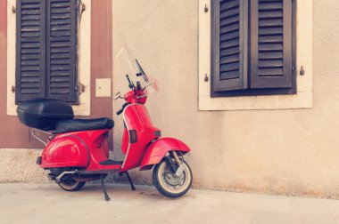 Kırmızı scooter duvarla boş sokakta park edilmiş. Vintage filtre ile işlenmiş post.