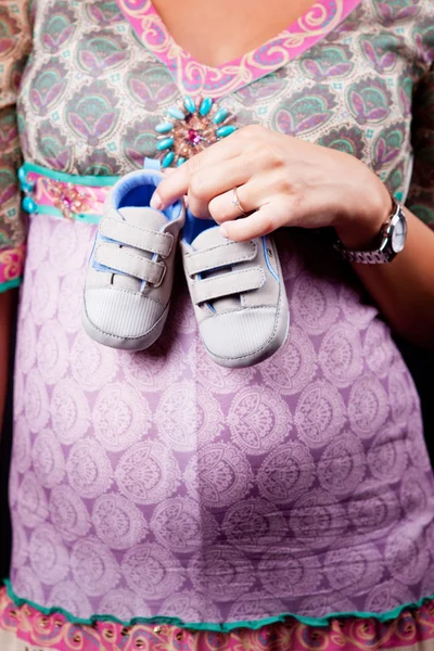 Pregnant woman holding baby boots — Stock Photo, Image