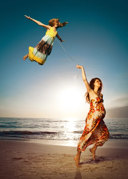 Mor och dotter på vackra stranden. Surrealistisk bild. — Stockfoto