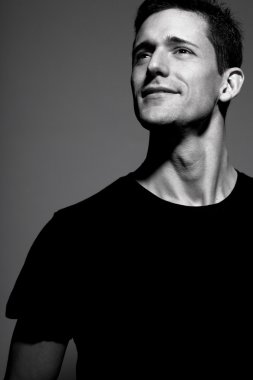 Siyah t-shirt gri arka plan üzerinde poz içinde adam.