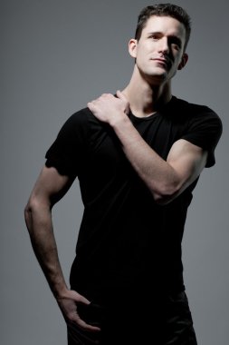 Siyah t-shirt gri arka plan üzerinde poz içinde adam.