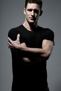 Siyah t-shirt gri arka plan üzerinde poz içinde adam.