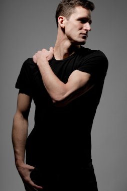 Siyah t-shirt gri arka plan üzerinde poz içinde genç adam.