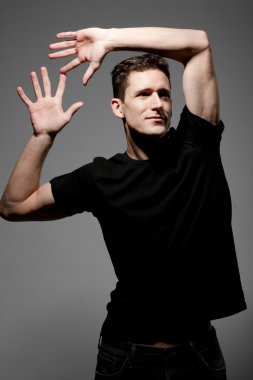 Siyah t-shirt gri arka plan üzerinde poz içinde genç adam.