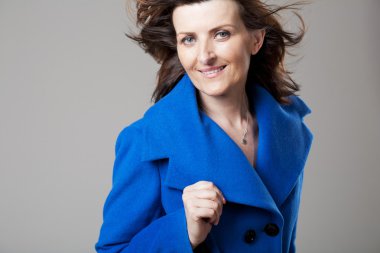 Gri arka plan üzerinde poz mutlu olgun kadın.