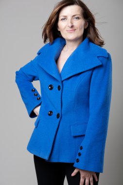 Gri arka plan üzerinde poz mutlu olgun kadın.