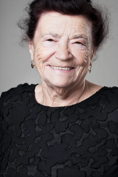 Glückliche ältere Dame posiert auf grauem Hintergrund. — Stockfoto