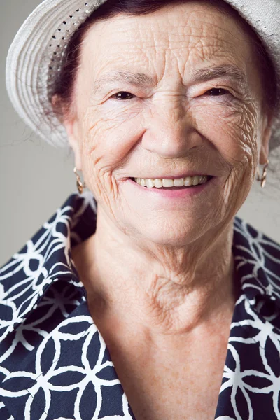 Seniorin posiert auf grauem Hintergrund. — Stockfoto