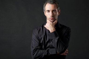 Yakışıklı adam koyu arka plan üzerinde siyah gömlekli poz.