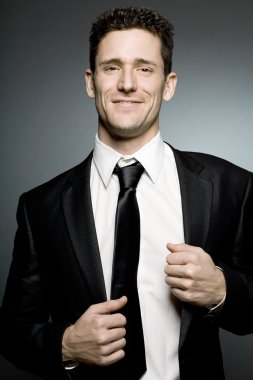 Siyah elbiseli pozitifliği ifade yakışıklı işadamı.