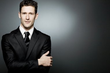 Siyah elbiseli pozitifliği ifade yakışıklı işadamı.