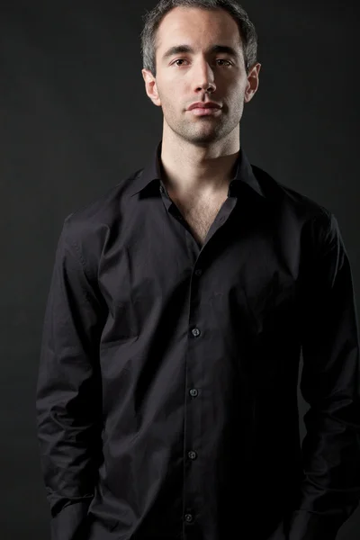 Άνθρωπος που θέτουν σε μαύρο πουκάμισο σε σκούρο φόντο στο στούντιο. — Φωτογραφία Αρχείου