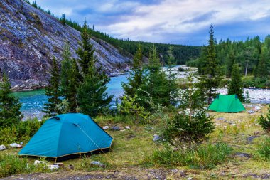 Çadır kampı bir yaz akşamı nehir kıyısındaki köknar ağaçlarının arasında.