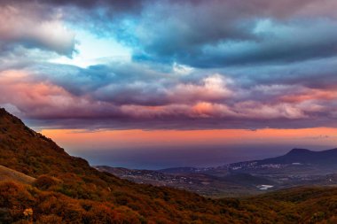 Gün batımında dağlardan tepelerin üzerinden ve Kırım 'da bir sonbahar akşamında denizi izle.