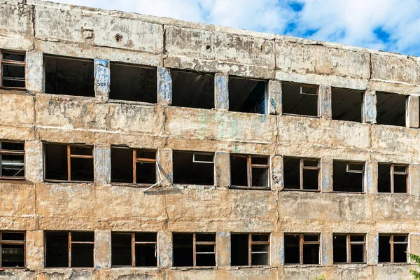 Parede de concreto de uma casa arruinada com janelas quebradas — Fotografia de Stock