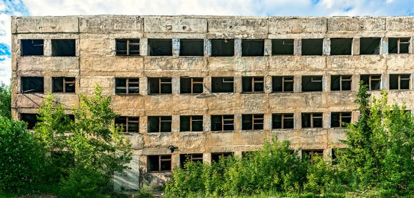 Förstörd övergiven stor betongbyggnad en sommardag Stockbild