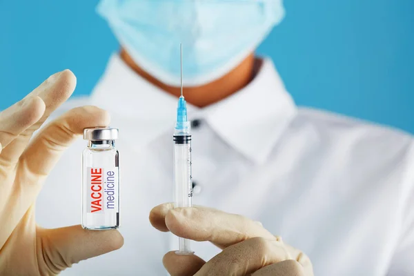 Vaccine ampoule in the hands of a physician researcher. Conceptual theme glass vials with clear liquid with syringe and hypodermic needle