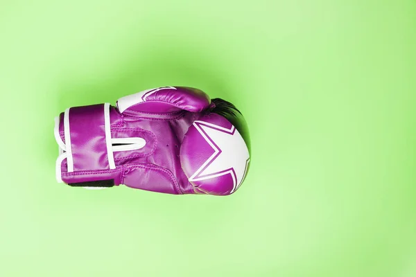 Pink Boxing glove on a green background. Close-up, Central composition. The concept of struggle and striving for victory. Square