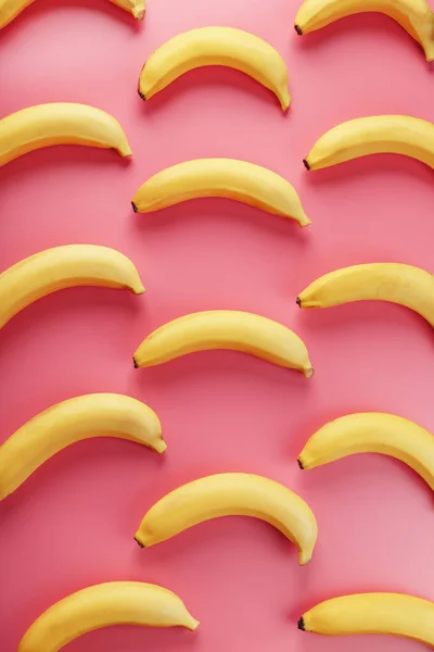 Bright pattern of yellow bananas on a pink background. View from above. Flat lay. Fruit patterns