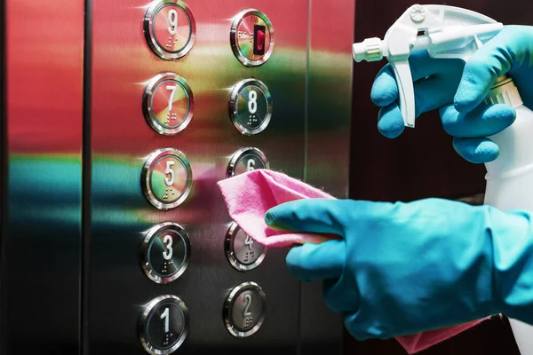 Disinfection and hygienic care using alcohol spray on the elevator button. Touching the area for cleaning and disinfection, prevent the spread of germs during COVID-19 infections